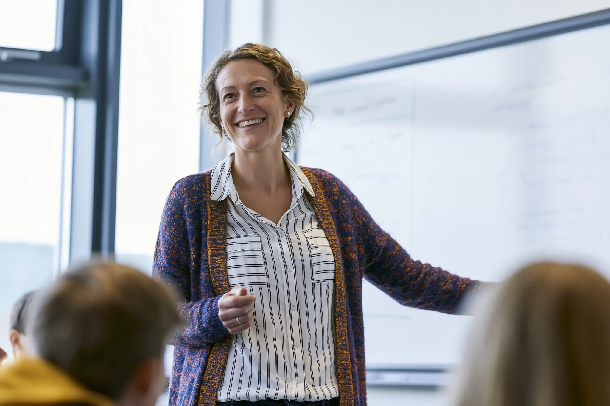 Teacher standing at the front of a classroom, smiling and engaging with pupils